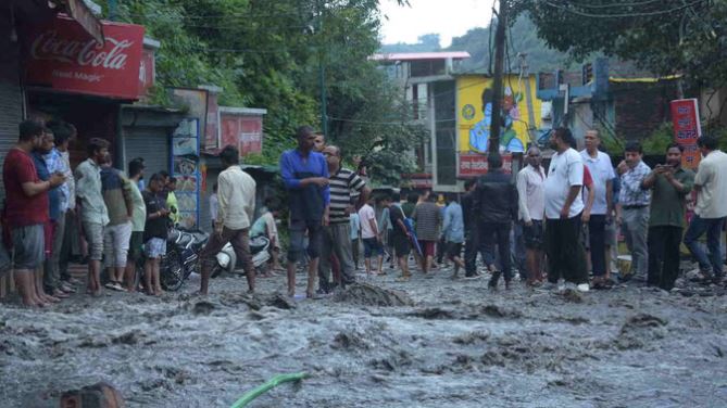 नदी के पार से अपने उजड़े घरों को निहारते लोग, भगवान से कर रहे सलामती की प्रार्थना