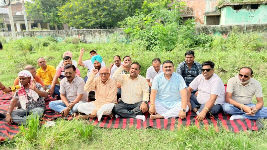 एक साल से खुदी पड़ी सड़क पर कांग्रेस का प्रदर्शन,गड्ढे में दरी बिछाकर धरने पर बैठे एक साल से खुदी पड़ी सड़क पर कांग्रेस का प्रदर्शन,गड्ढे में दरी बिछाकर धरने पर बैठे